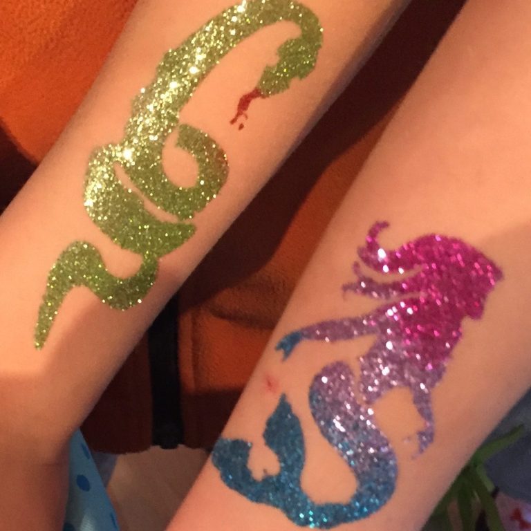 Glitzertattoos einer Meerjungfrau in rosa-blau und einer grünen Schlange.