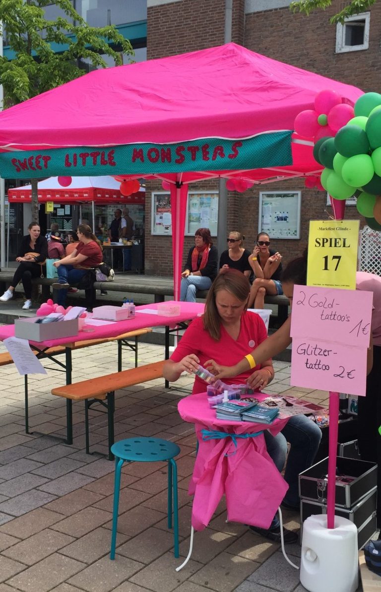 Sweet Little Monsters Stand auf einem Fußweg während eines Stadtfestes.